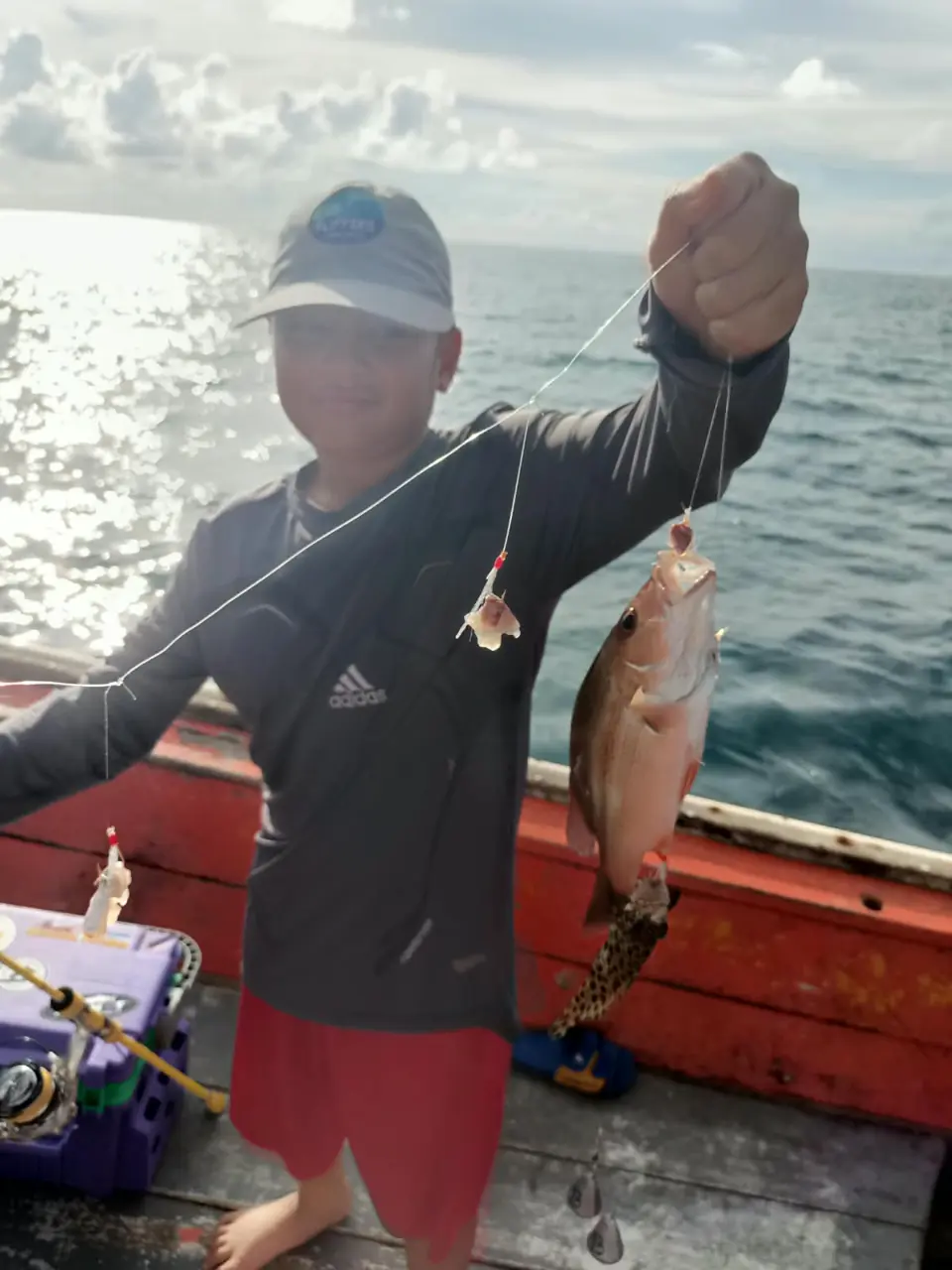 Gast zeigt einen frisch gefangenen Fisch auf dem Angelboot