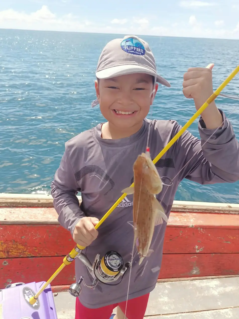 Gast zeigt einen frisch gefangenen Fisch auf dem Angelboot