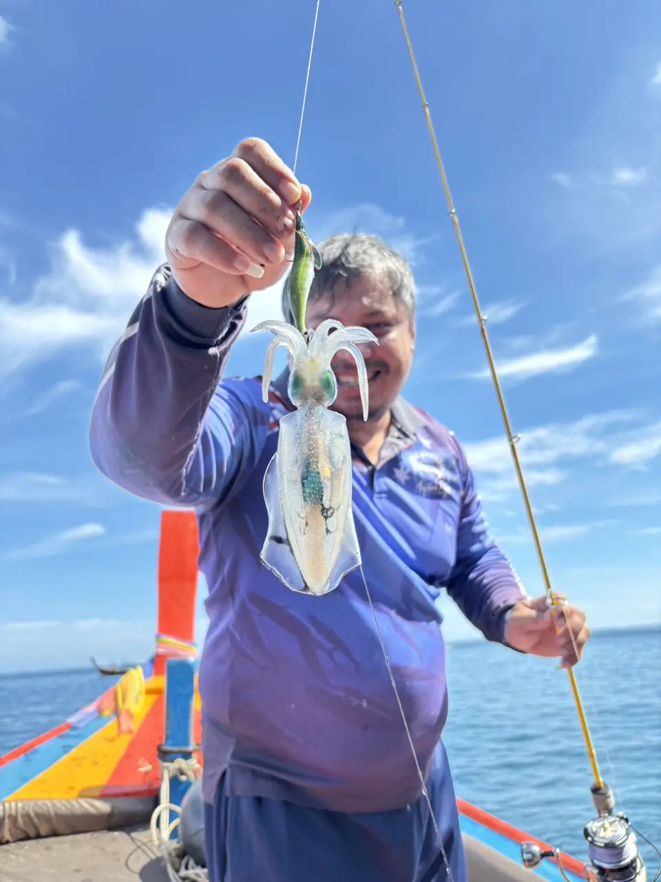 Gast zeigt einen frisch gefangenen Fisch auf dem Angelboot